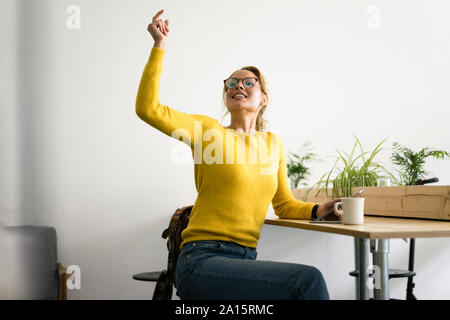 Jeune femme assise dans un café, en cliquant sur les doigts pour commander quelque chose Banque D'Images