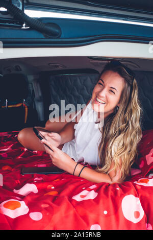 Très jolie jeune femme à l'intérieur d'un camping à l'aide de van comprimé. Banque D'Images