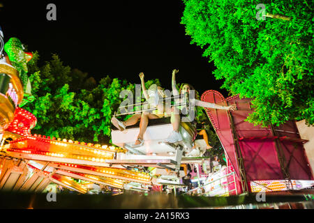 Deux jeunes femmes excitées dans un parc d'ride sur une fête foraine la nuit Banque D'Images