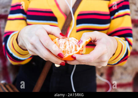 Woman's hands peeling la mandarine, close-up Banque D'Images