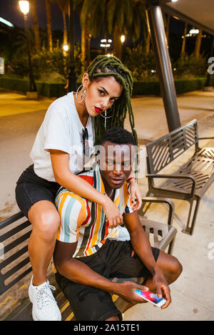 Cool jeune couple sur un banc dans la nuit dans la ville Banque D'Images