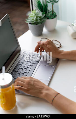 Close-up of woman using laptop at desk Banque D'Images