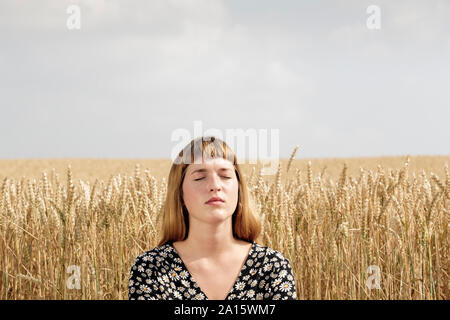 Portrait of young woman with eyes closed relaxing in front of grain field Banque D'Images