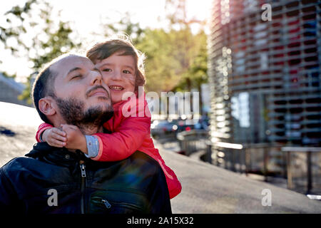 Petite fille de 2 ans, serrant son père dans la ville en hiver. Barcelone, Espagne Banque D'Images