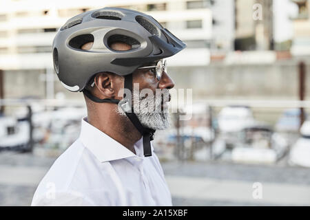 Profil de man avec barbe grise portant des lunettes et casque de vélo Banque D'Images