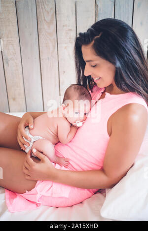 Happy mother sitting on bed with baby boy Banque D'Images