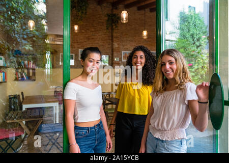 Portrait of smiling trois jeunes femmes à la terrasse d'un café Banque D'Images
