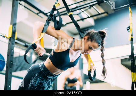 Jeune femme faisant traning suspension dans la salle de sport Banque D'Images