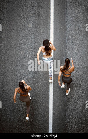 Vue du haut de trois jeunes femmes sportive s'exécutant sur une rue Banque D'Images