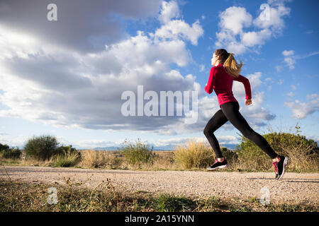 Young woman jogging on road in countryside Banque D'Images