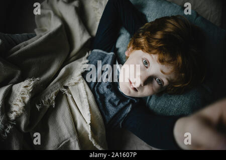 Portrait de jeune garçon roux lying on couch looking up Banque D'Images