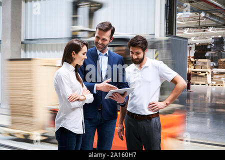 Smiling businessman with tablet et employés de parler dans une usine Banque D'Images