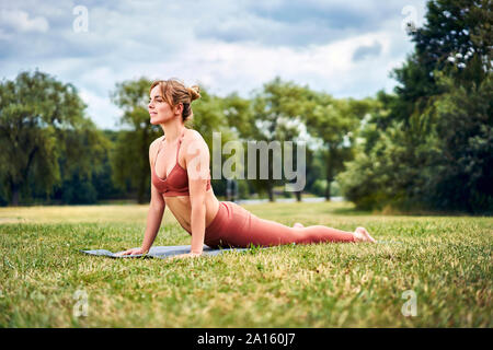 Cobra woman doing yoga pose au cours de la formation dans le parc Banque D'Images