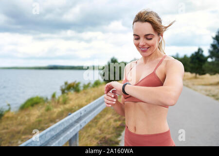 Portrait de femme fit contrôler smartwatch extérieur lors de séance de jogging Banque D'Images