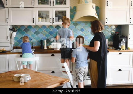 La cuisine de la mère avec ses trois fils dans la cuisine Banque D'Images