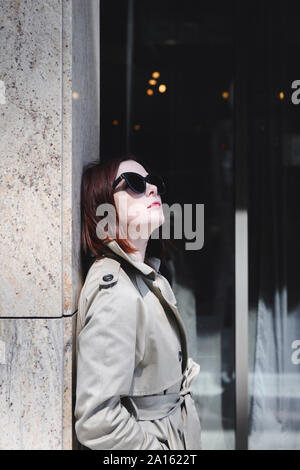 Portrait d'une femme élégante avec des lunettes de soleil et imperméable Banque D'Images