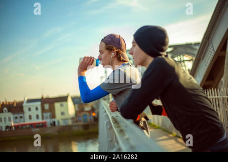 Deux jeunes hommes de l'eau potable après une course par River Thames, London, UK Banque D'Images