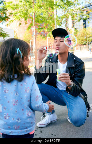 Père et fille jouant avec des bulles de savon en plein air Banque D'Images