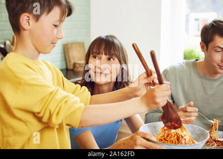 Mère mange du spaghetti avec ses fils dans la cuisine Banque D'Images