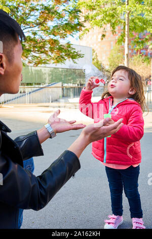 Père et fille jouant avec des bulles de savon en plein air Banque D'Images