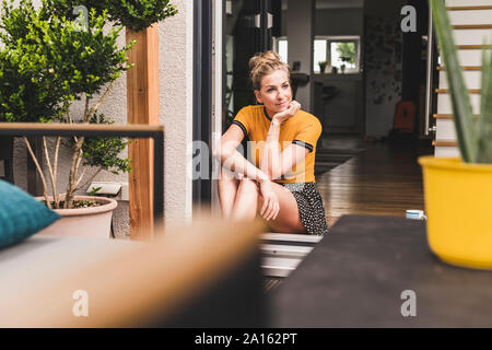 Relaxed woman sitting at exposée à la maison de la porte Banque D'Images