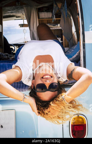Femme avec des lunettes de soleil couché dans van, looking at camera Banque D'Images
