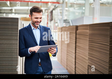 Smiling businessman using tablet en usine-entrepôt Banque D'Images