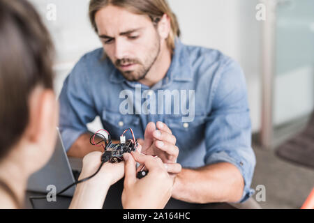 Jeune homme et femme travaillant sur le matériel informatique in office Banque D'Images