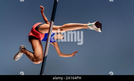 Worm's eye view of female runner crossing hurdle Banque D'Images