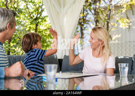 Heureuse mère et fils fiving haut après avoir gagné un match sur terrasse Banque D'Images