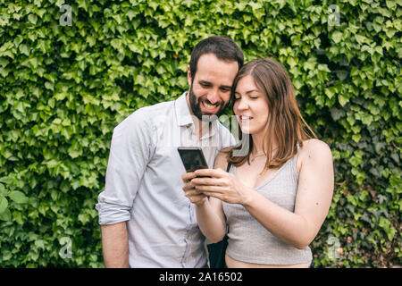 Happy young couple sharing cell phone Banque D'Images