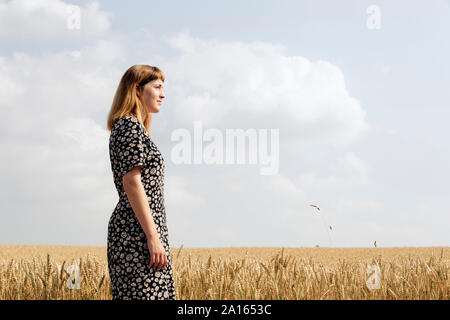 Jeune femme portant robe floral design standing in grain field Banque D'Images