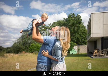 Heureux père de mère soulevant baby girl in garden Banque D'Images