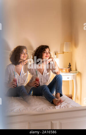 Ambiance jeune femme assise sur le lit avec boisson saine Banque D'Images
