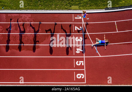 Vue aérienne d'une exécution et couché jeunes femmes athlètes sur une piste en tartan Banque D'Images