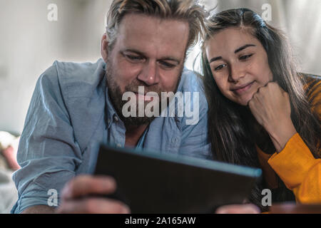 Couple lying on the floor at home looking at tablet Banque D'Images