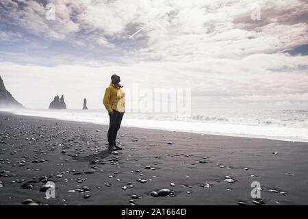 Man marche sur une plage de lave en Islande Banque D'Images