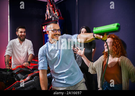 Happy friends playing et tir avec des pistolets dans une salle de jeux électroniques Banque D'Images