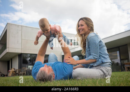 Heureux père de mère soulevant baby girl in garden Banque D'Images