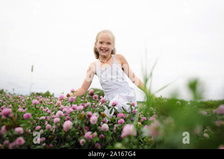 Smiling girl avec bouquets d'exécution sur le champ de trèfle Banque D'Images