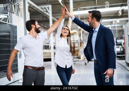 Happy businessman et employés dans une usine fiving haut Banque D'Images