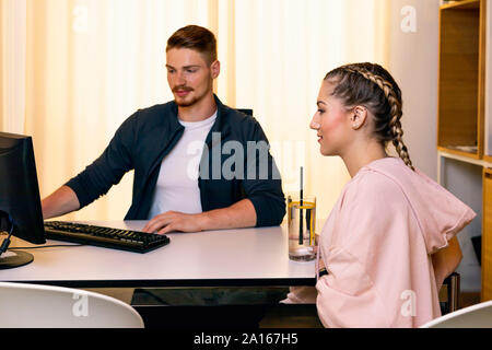 Jeune femme parlant à l'employé de bureau dans une salle de sport Banque D'Images