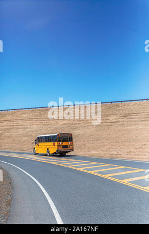 Autobus scolaire jaune sur l'autoroute contre ciel bleu clair au cours de journée ensoleillée Banque D'Images