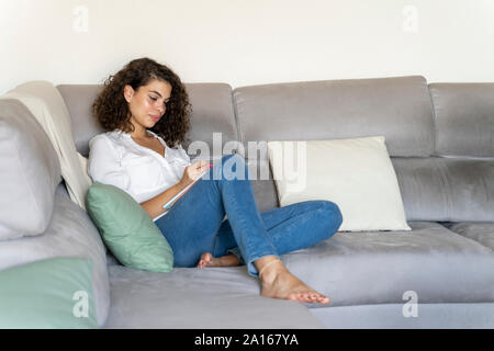 Jeune femme en prenant des notes sur la table à la maison Banque D'Images