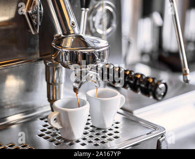 Deux tasses à espresso se rempli dans un portafilter machine Banque D'Images