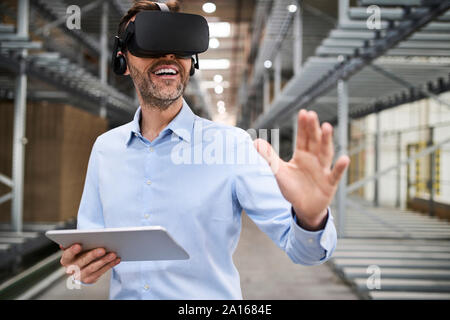 Businessman with tablet portant des lunettes VR en usine Banque D'Images