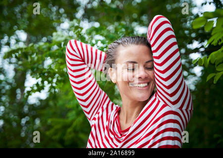 Portrait de femme heureuse avec des cheveux humides portant haut rayé dans la nature Banque D'Images