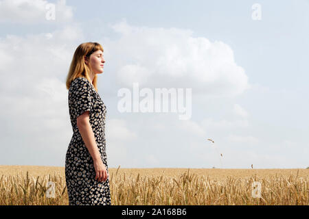 Jeune femme portant robe floral design standing in grain field Banque D'Images