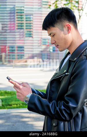 Young man using cell phone, Barcelone, Espagne Banque D'Images