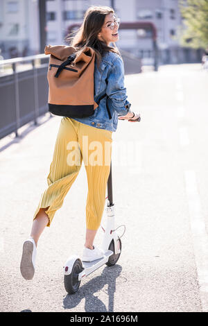 Happy young woman riding scooter électrique sur un pont Banque D'Images